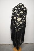 A large early 20th century silk shawl, having extensive intricate cream floral embroidery and deep