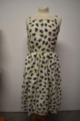 A 1950s cotton day dress, having purple rose pattern and pleated skirt, larger size.