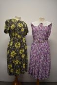 Two 1950s day dresses, both having abstract floral patterns, yellow and green dress having half belt