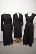 A 1930s floor length black gown, having tie belt to draw in waist and buttons to nape, balloon
