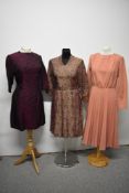 Three vintage dresses, including 1950s pink and gold brocade dress with pleated skirt and belt.