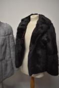 Two rabbit fur coats, one grey and the other black.