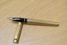 A Sheaffer Targa 1009 converter fill fountain pen in gold with engine turned decal having Sheaffer