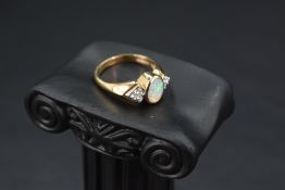An opal dress ring having a trio of diamond chips to each shoulder on a 9ct gold moulded loop,