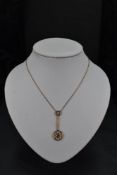 An Edwardian yellow metal pendant stamped 15ct having seed pearl and blue topaz decoration on a