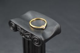 A diamond solitaire ring, approx 0.125ct in a collared mount on a yellow metal loop stamped 18ct/