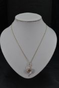 A 9ct gold pendant having a central facet cut pale pink stone, possibly a pink topaz, within an open
