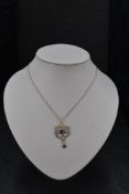 An Edwardian yellow metal pendant stamped 9ct having amethyst and split pearl decoration on a yellow