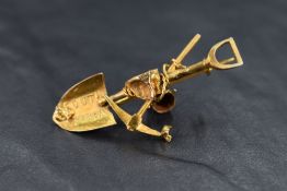 A South African yellow metal miner's brooch stamped 15C featuring spade, pick & bucket, approx