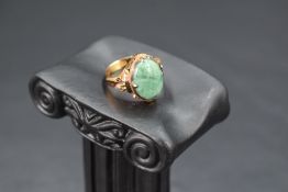 An oval jade cabochon ring in a four claw collared mount on a Chinese gold loop, size K and approx
