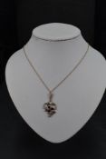 An Edwardian yellow metal pendant stamped 9ct having garnet and split pearl decoration on a yellow