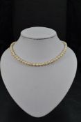 A string of cultured pearls of even form with a yellow metal box clasp, approx 16'
