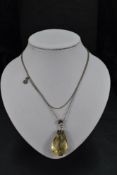 A facet cut citrine pendant of tear drop form having white metal fittings on a long white metal