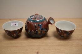 A Japanese glazed pottery teapot, decorated with traditional figures, measuring 11cm tall,