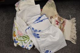 A selection of vintage table linen, including intricately embroidered items, crochet edged