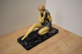 A modern Art Deco or Nouveau influenced study of a seated maiden holding a shell to her ear, cast-