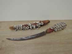 A Cowri Shell covered Dagger and Sheath, curved blade with possible engraving seen, blade length