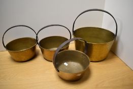 A group of four brass preserve/jam pans, one large and three small, each with iron over handle.