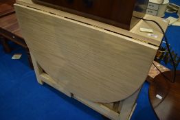A modern laminate drop leaf table with nesting chairs under