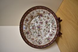 A large continental charger, having hand painted decoration of sprigs of flowers in pinks, brown,