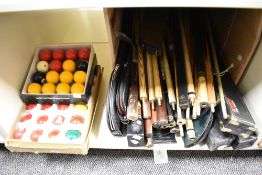 A collection of pool / snooker balls in boxes and a large amount of cues and some cases.