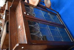 A late 19th or early 20th Century oak bookcase having shaped leaded glass doors, in the Art