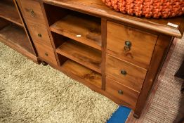 A modern hardwood TV cabinet or small sideboard, having central open shelves flanked by two banks of