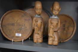 Three carved plaques having traditional scenes of people and animals and two carved women holding
