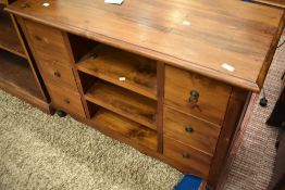 A modern hardwood TV cabinet or small sideboard, having central open shelves flanked by two banks of