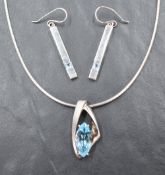 A silver pendant and chain having a blue Topaz stone in a stylised mount, with matched loop drop