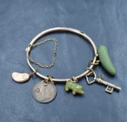 A vintage yellow metal hinged bangle of slim buckled belt form having five attached charms including