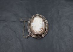A conch shell cameo brooch depicting Medusa in a decorative white metal mount, no marks but presumed