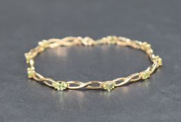 A nine carat gold peridot bracelet, the infinity design links interspersed with nine oval cut