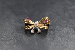 A 9ct gold brooch modelled as a small bow having diamond and ruby chip decoration, approx 3.2g