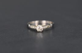 A diamond solitaire ring, approx 0.25ct in a raised claw set mount with diamond chip set shoulders