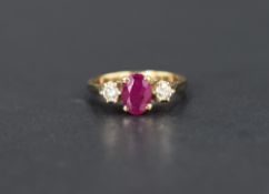 A ruby and diamond trilogy ring, the central oval cut ruby, approx 0.70ct, flanked by two