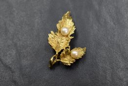 An 18ct gold brooch having a detailed double leaf design set with two cultured pearls, approx 6.3g
