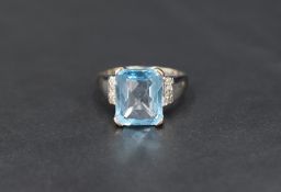 A facet cut rectangular blue topaz ring having a four claw raised mount and diamond chip set