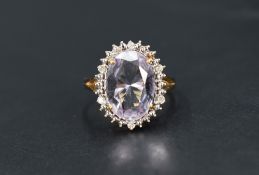An amethyst and diamond cluster ring, the central oval cut amethyst measuring approximately 13.2 L x