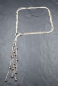 A silver five strand tassel necklace having iridescent pearl decoration and a loop connector