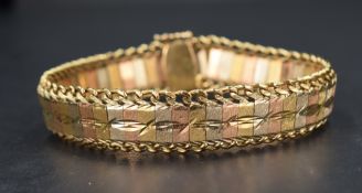 A 1980's three coloured yellow metal articulated bracelet having brushed and cut panels with a