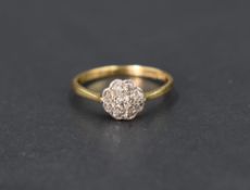 A diamond daisy cluster ring having a cushion mount on a yellow metal loop stamped 18ct, size K &