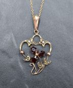 An Edwardian yellow metal pendant stamped 9ct having garnet and split pearl decoration on a yellow