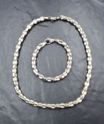 A silver necklace and matching bracelet having alternate brushed and polished links, bearing