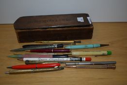 A 20th Century wooden sliding pencil box, measuring 21cm long, with vintage pens including a