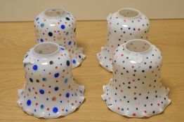 Four fluted opaque glass lamp shades, having later added spot decoration.