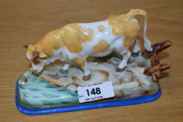 A Continental porcelain cow study, modelled in a naturalistic setting and hand-decorated in