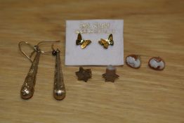 A collection of yellow metal earrings comprising a pair of decorative drop earrings, a pair of