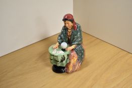A Royal Doulton bone china figurine 'Fortune Teller' modelled seated at a table with crystal ball