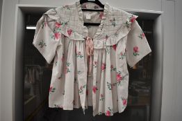 A 1950s cotton bed jacket, having bright rose pattern, quilted yolk and ribbon to fasten.